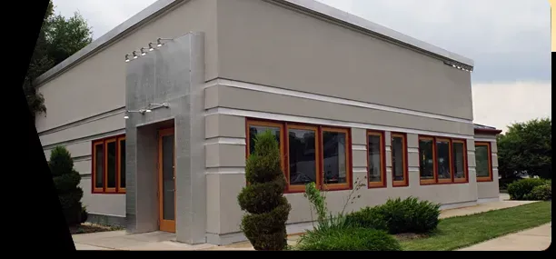 Modern, gray building with brown-framed windows and a landscaped front yard.
