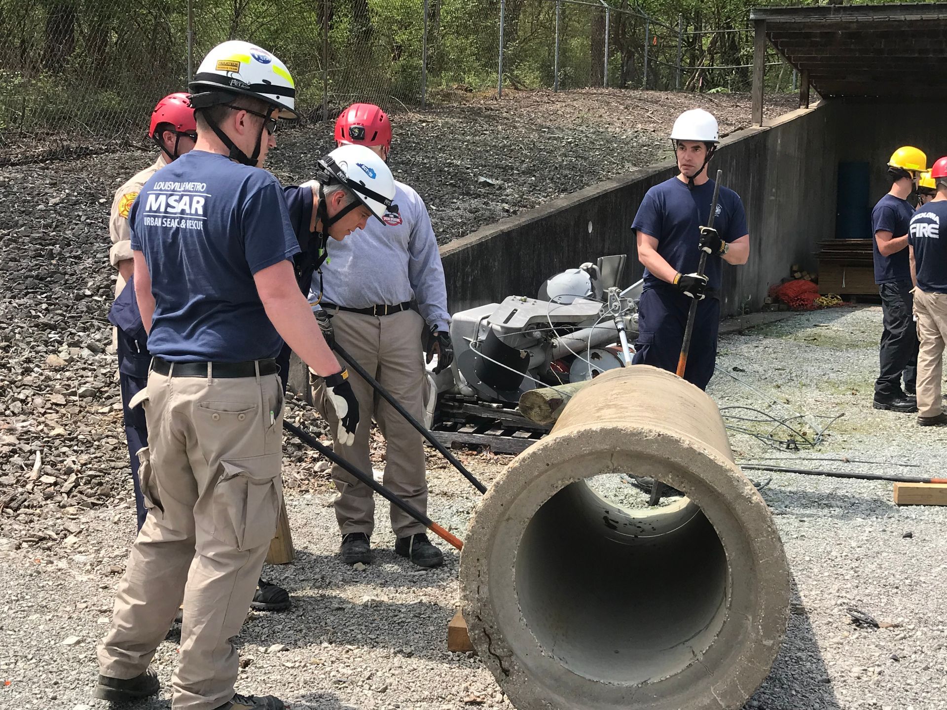 A group of men are standing around a large concrete pipe.