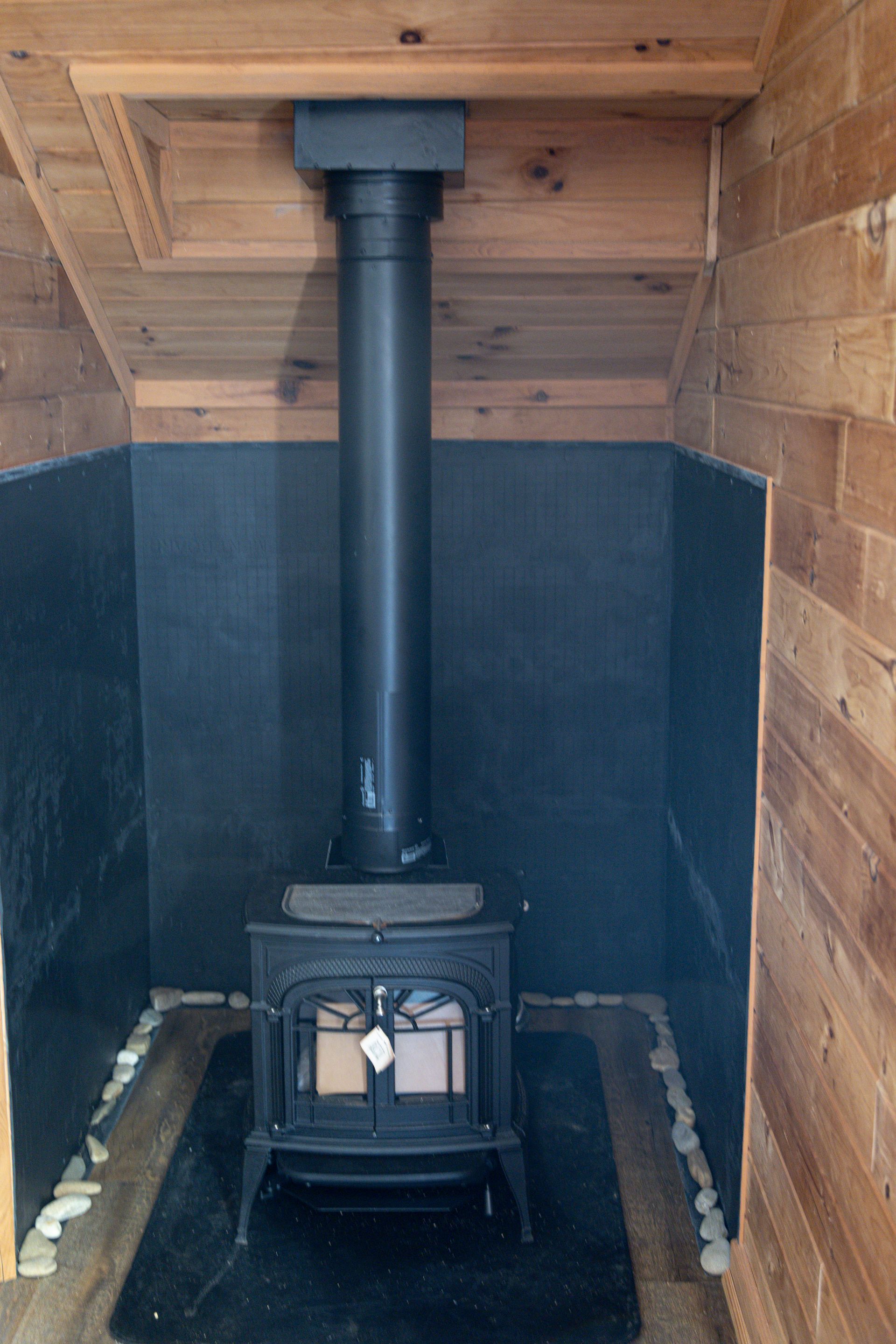 Wood stove with black pipe in a wooden alcove.