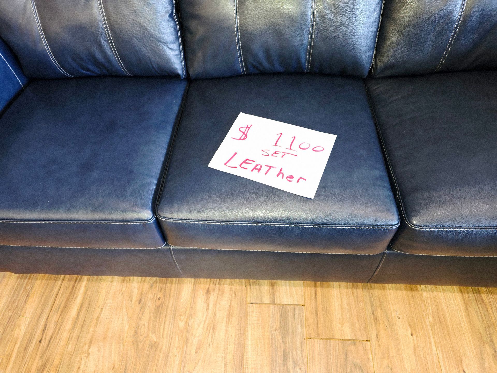 Dark blue leather couch with a white sign reading