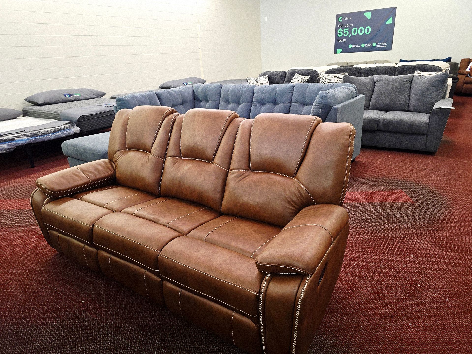 A brown leather sofa in a furniture store showroom with other sofas in the background.
