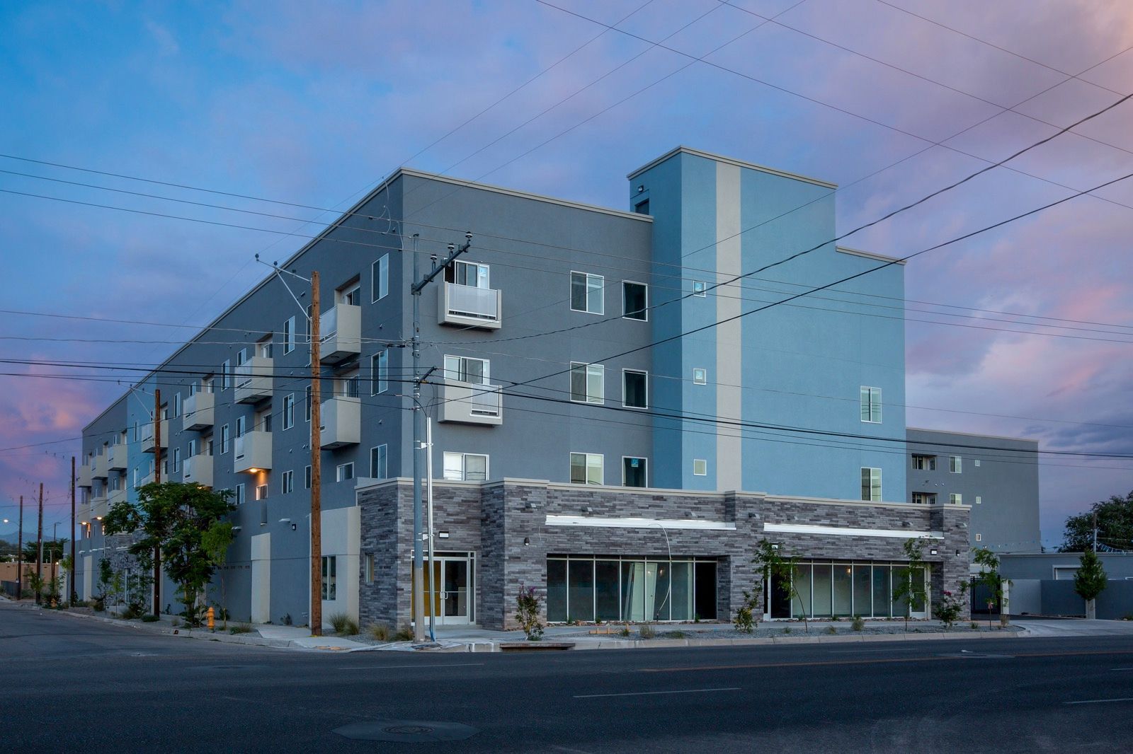 A large apartment building is sitting on the corner of a city street.
