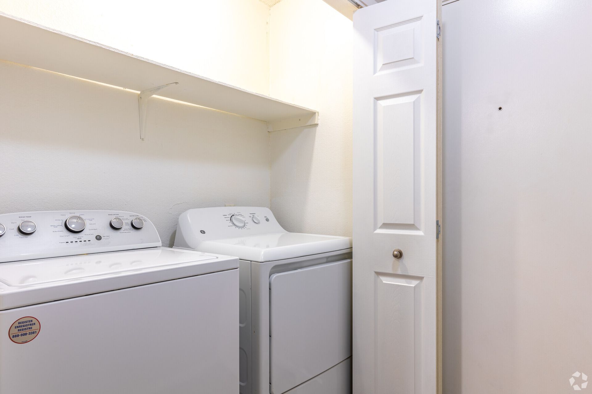 A washer and dryer are in a laundry room next to a door.