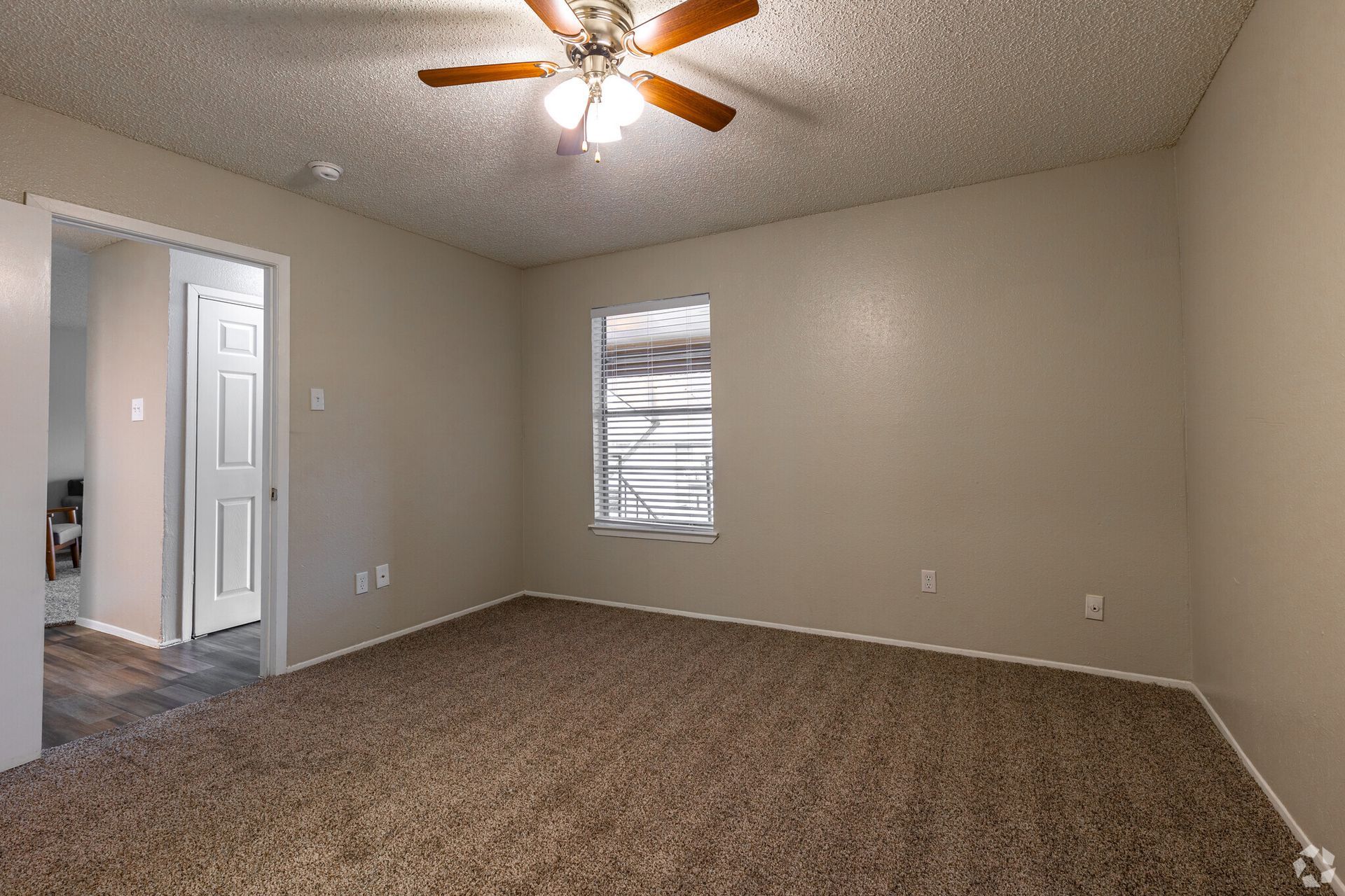 An empty room with a ceiling fan and a window.