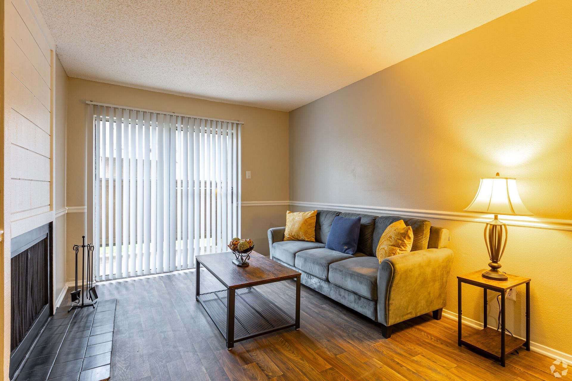 A living room with a couch , coffee table , fireplace and sliding glass doors.