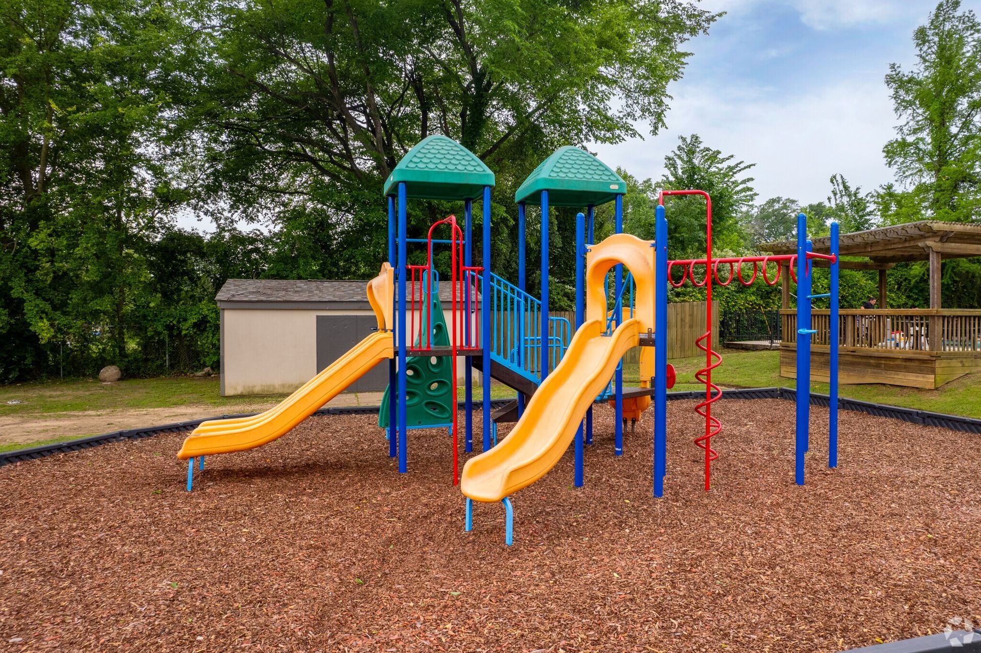 A colorful playground with two slides and a swing set in a park.