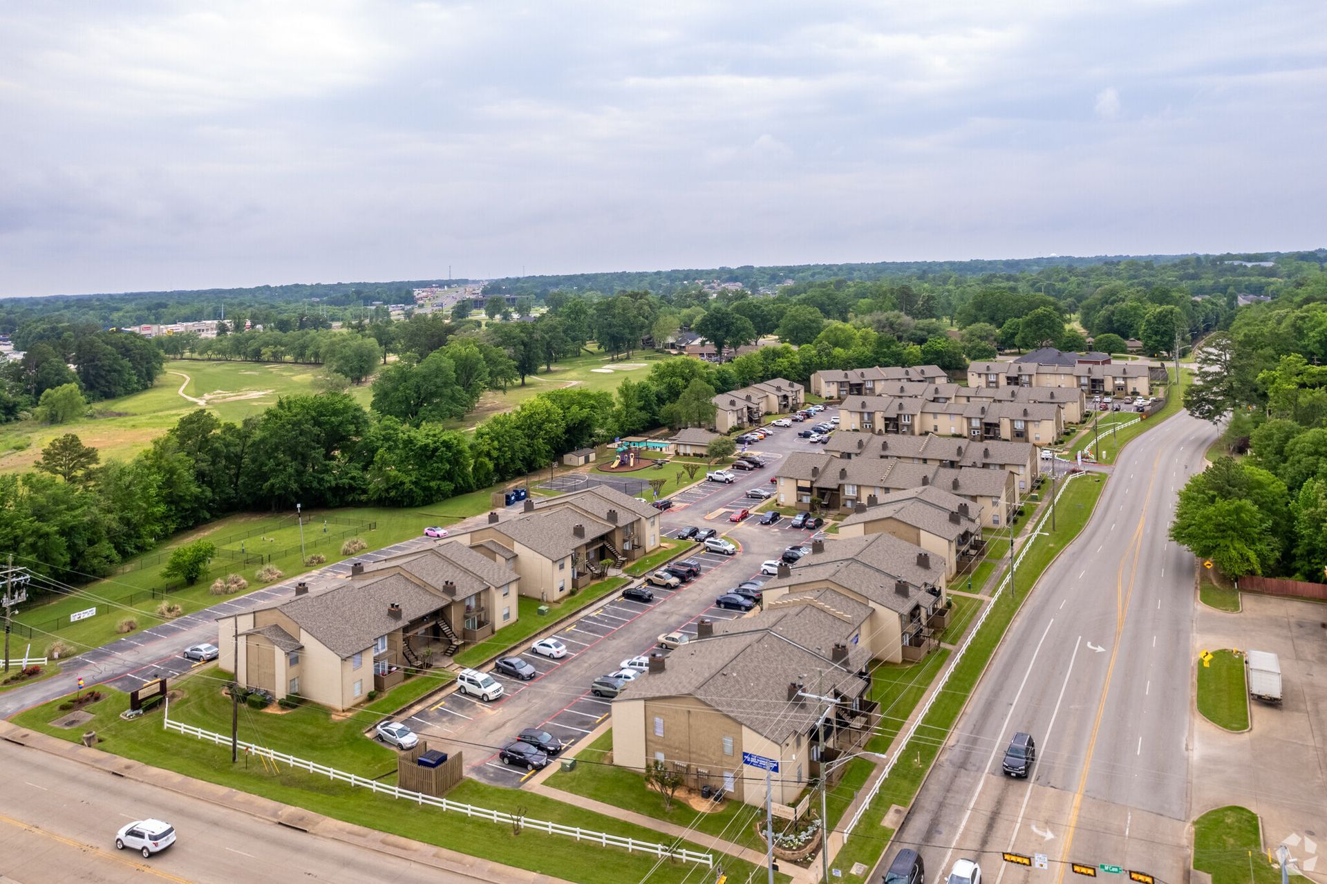 An aerial view of a residential area with a parking lot and a road.