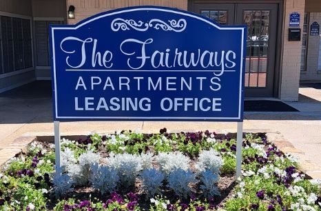 A blue sign for the fairways apartments leasing office