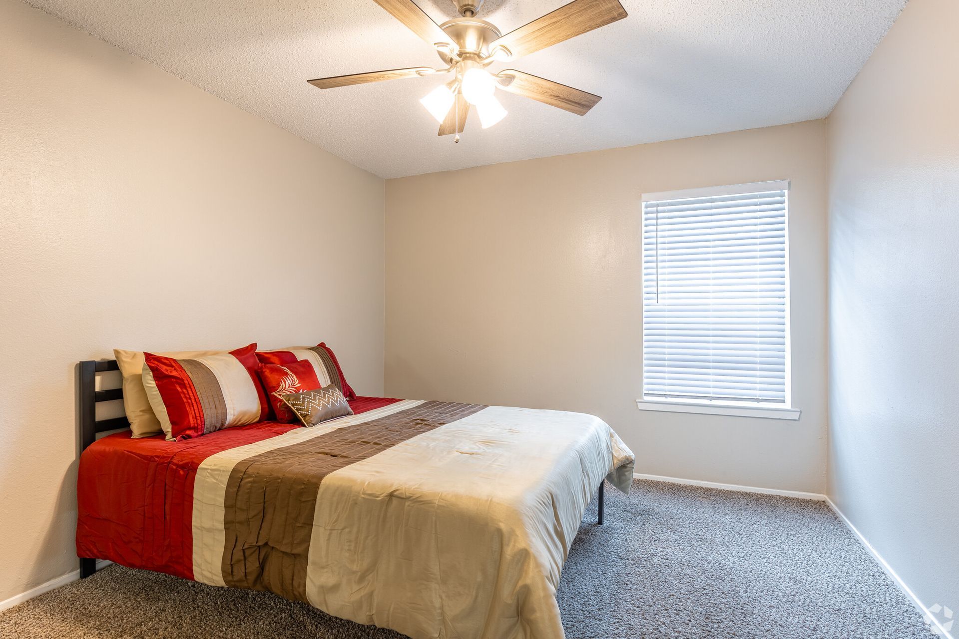A bedroom with a bed and a ceiling fan.