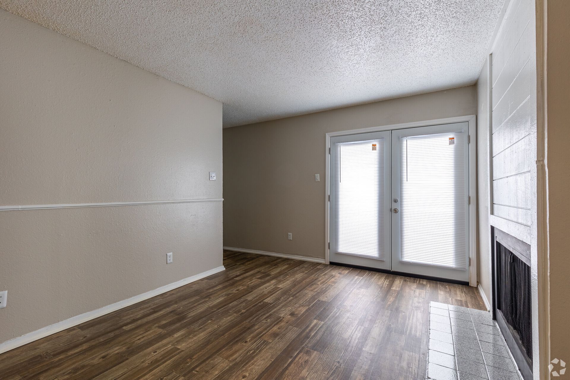 An empty living room with hardwood floors and a fireplace.