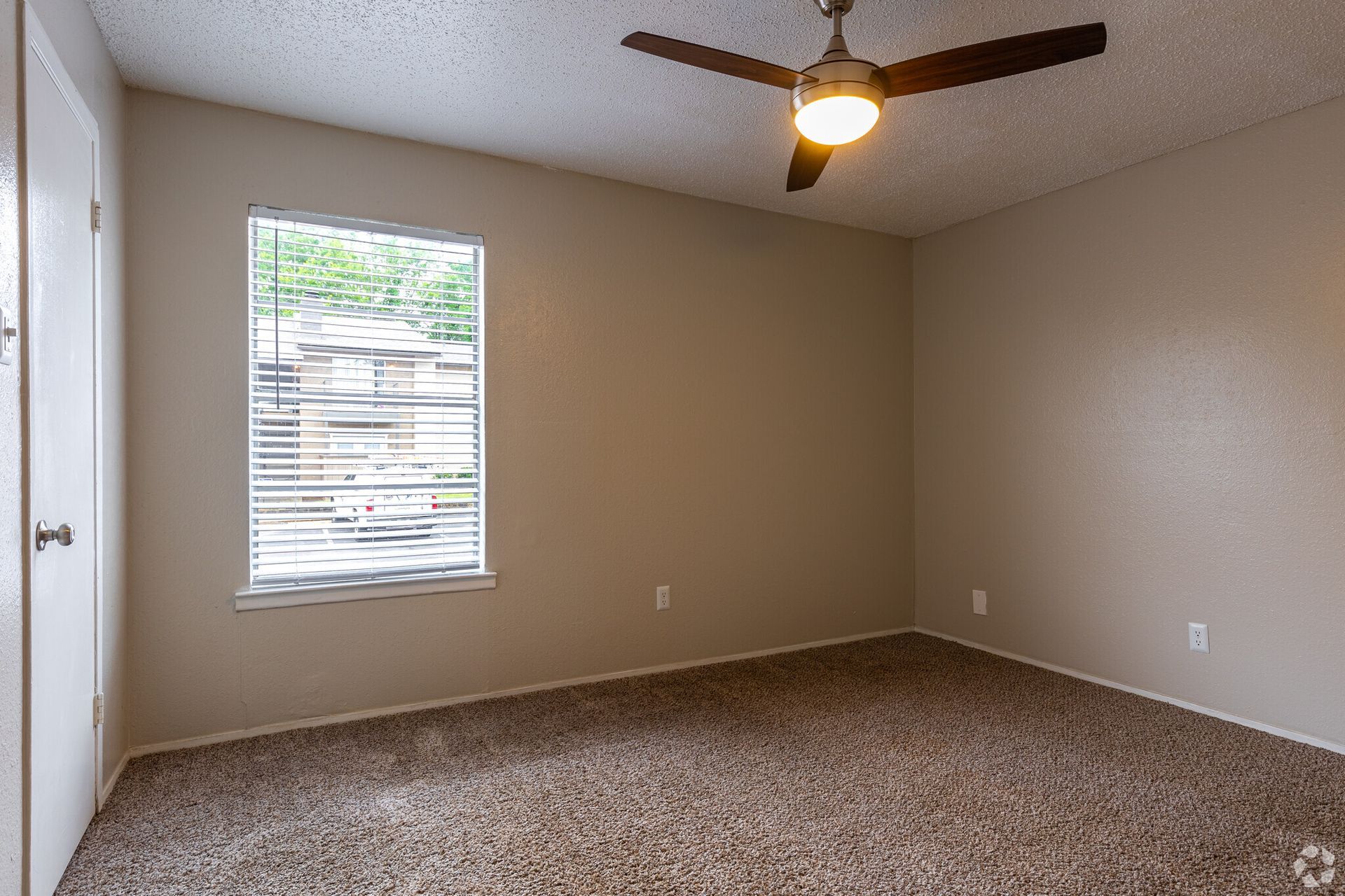 An empty bedroom with a ceiling fan and a window.