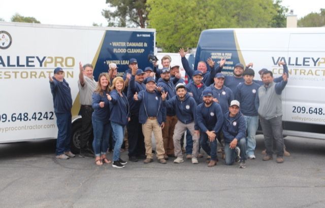 A group of people posing in front of valley pro restoration vans