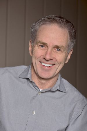 A man in a grey shirt is smiling for the camera.