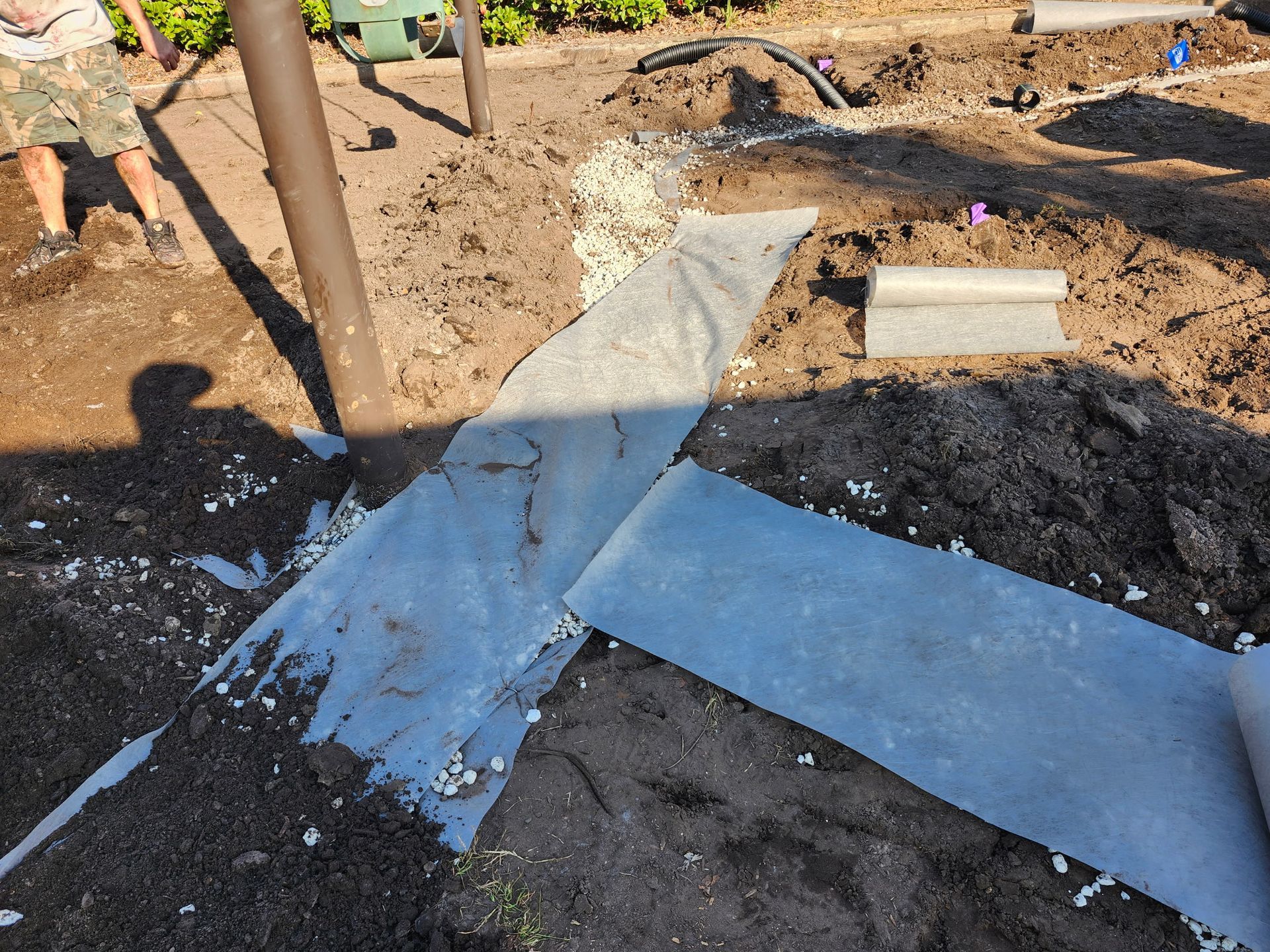 Construction site with fabric and gravel on the ground. A person is visible at the left.