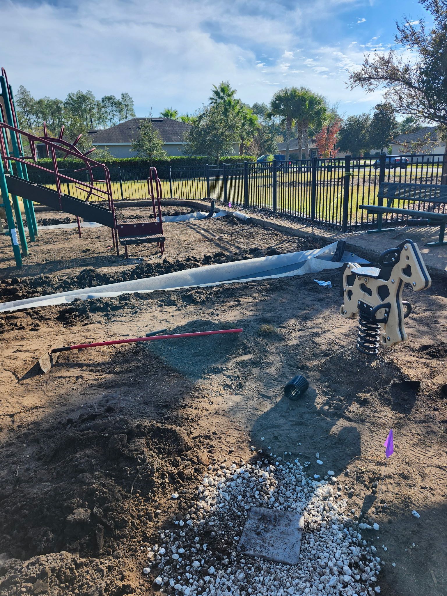 Playground construction site with exposed soil, equipment, and a spring rider.