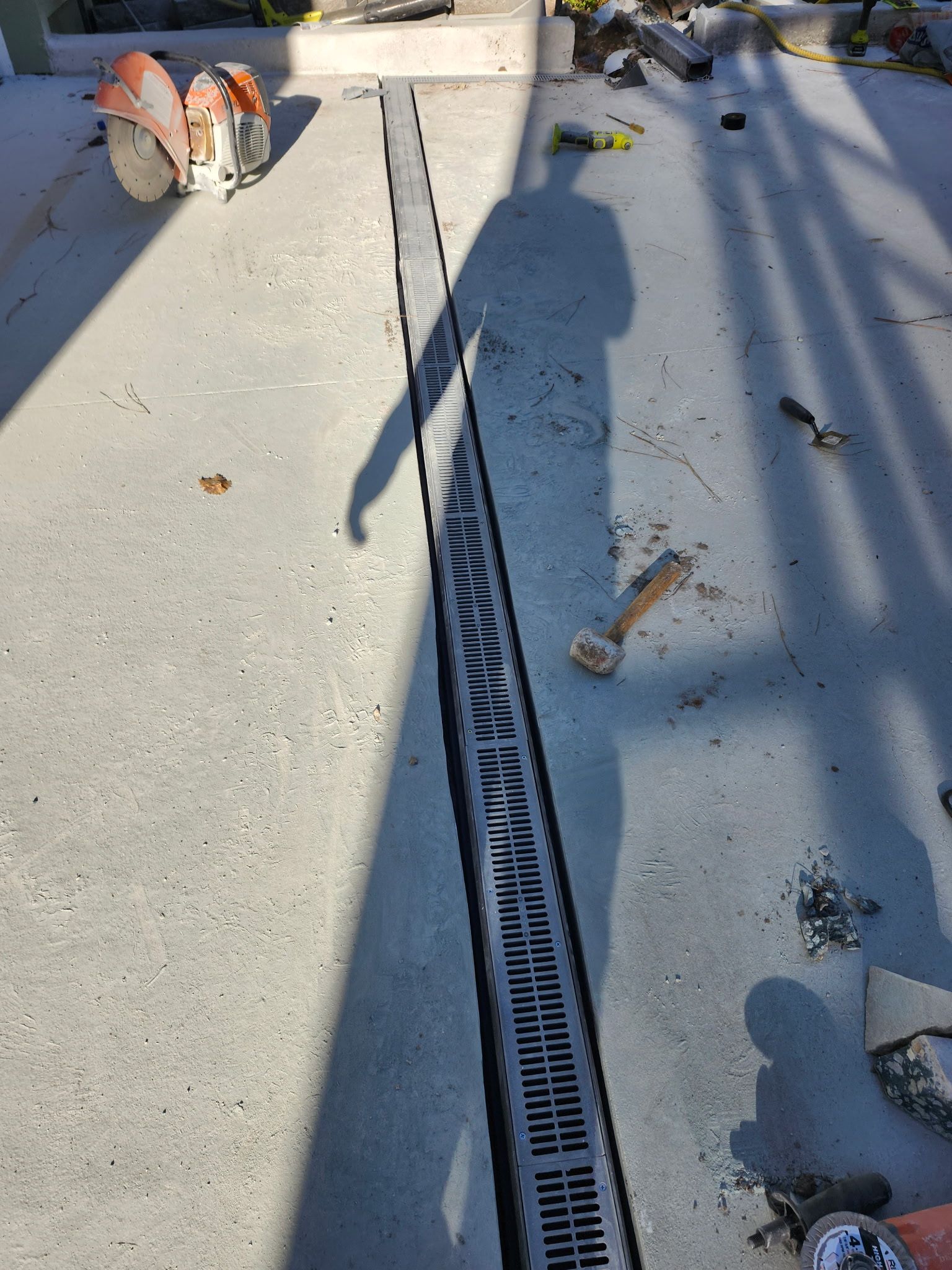 Concrete channel drain installed in concrete, tools nearby.