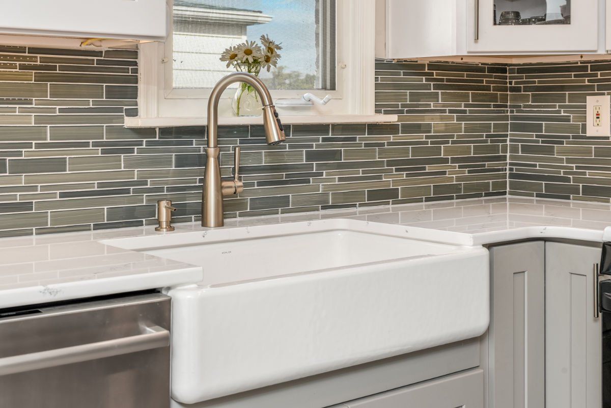 A kitchen with a white farmhouse sink and a stainless steel dishwasher.