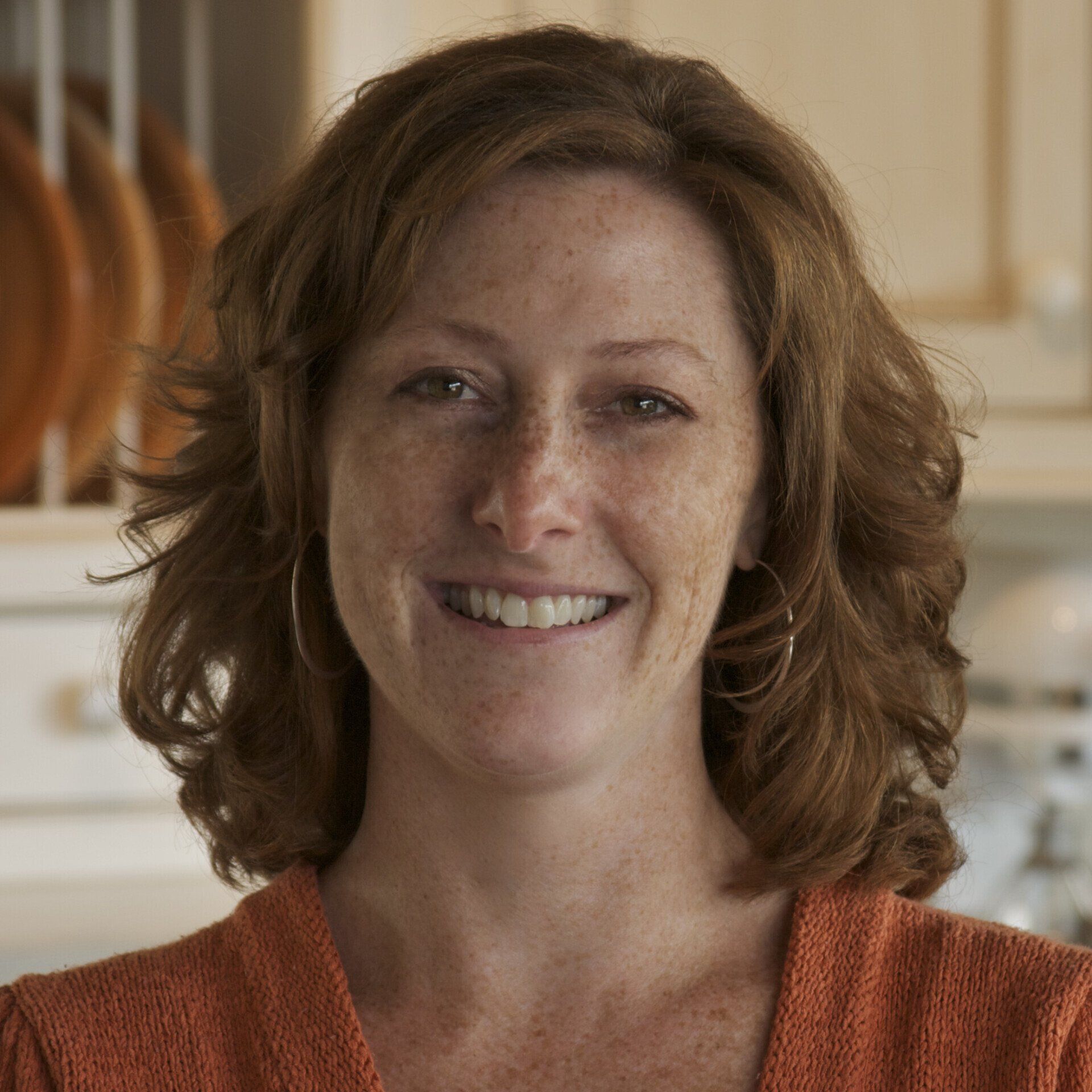 A woman with red hair and freckles smiles for the camera