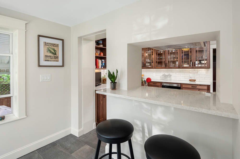 A kitchen with a bar and two stools in it.