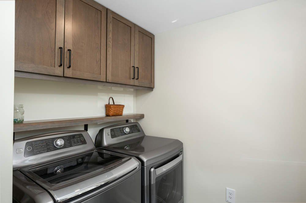 A laundry room with a washer and dryer and wooden cabinets.