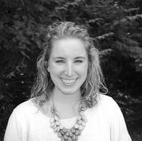 A black and white photo of a woman wearing a necklace and smiling.