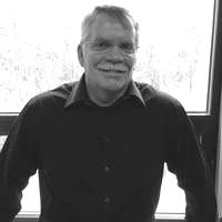 A black and white photo of a man standing in front of a window.