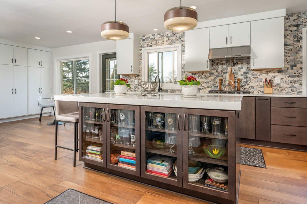 A kitchen with a large island and glass cabinets.
