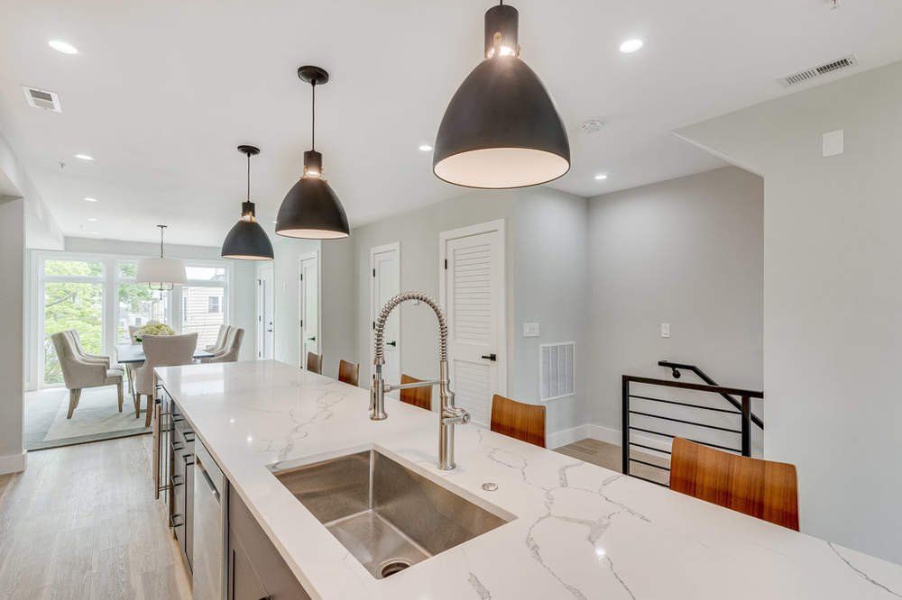 A kitchen with a stainless steel sink and white counter tops.