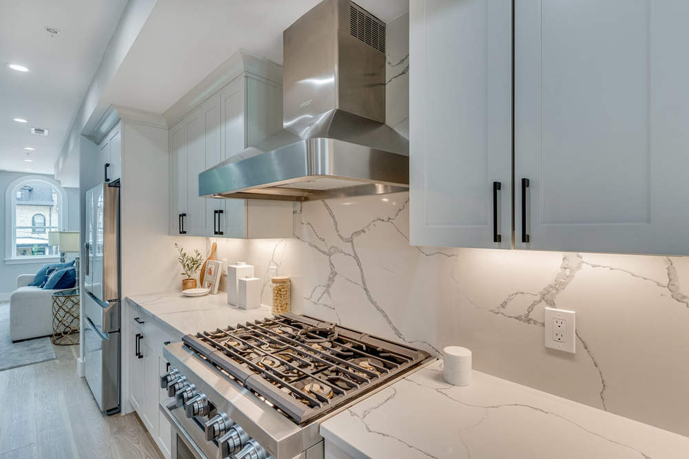 A kitchen with white cabinets , stainless steel appliances , and a stove top oven.