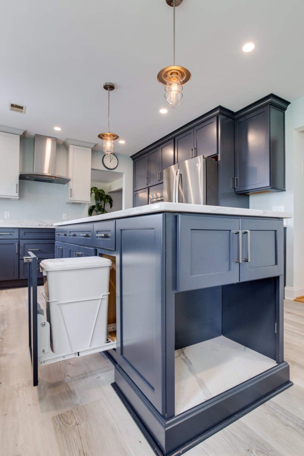 A kitchen with a trash can in the middle of the island.
