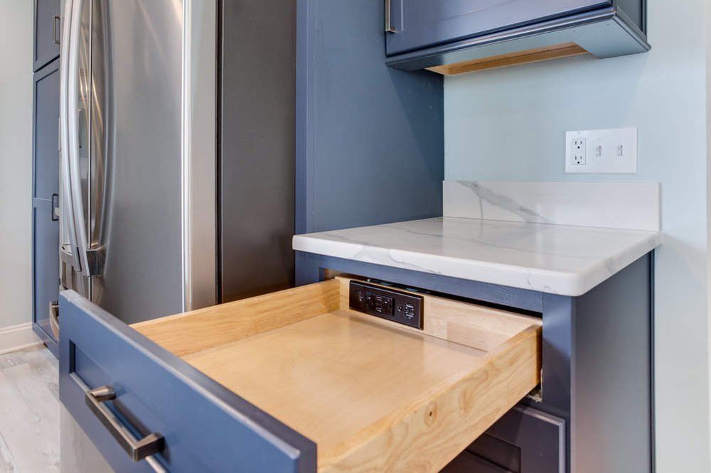 A kitchen with a stainless steel refrigerator and a wooden drawer.