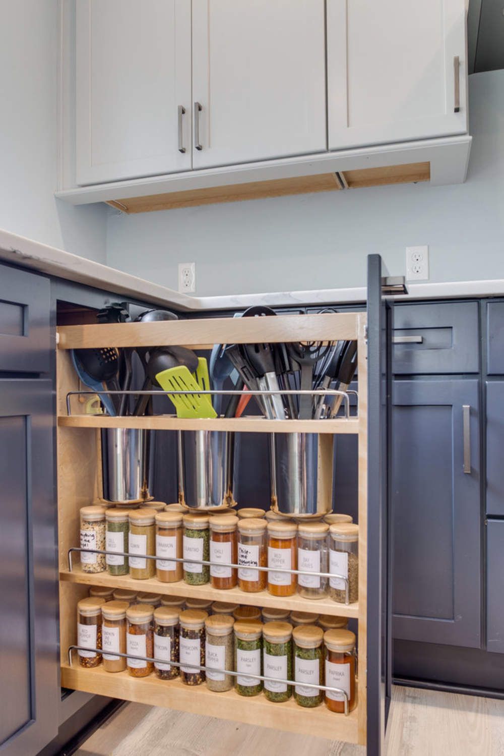 A kitchen with a pull out spice rack and utensils.