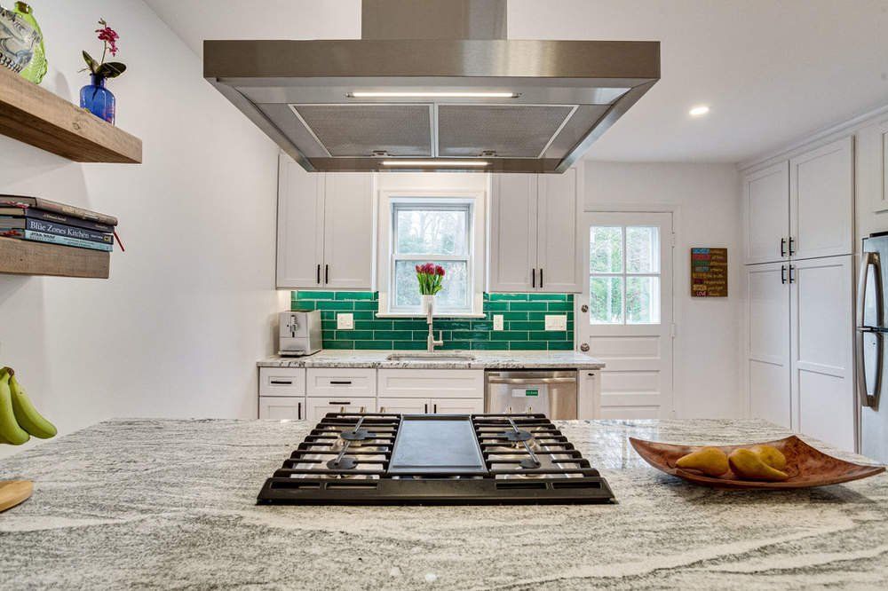 A kitchen with a stove top oven and a stainless steel hood.