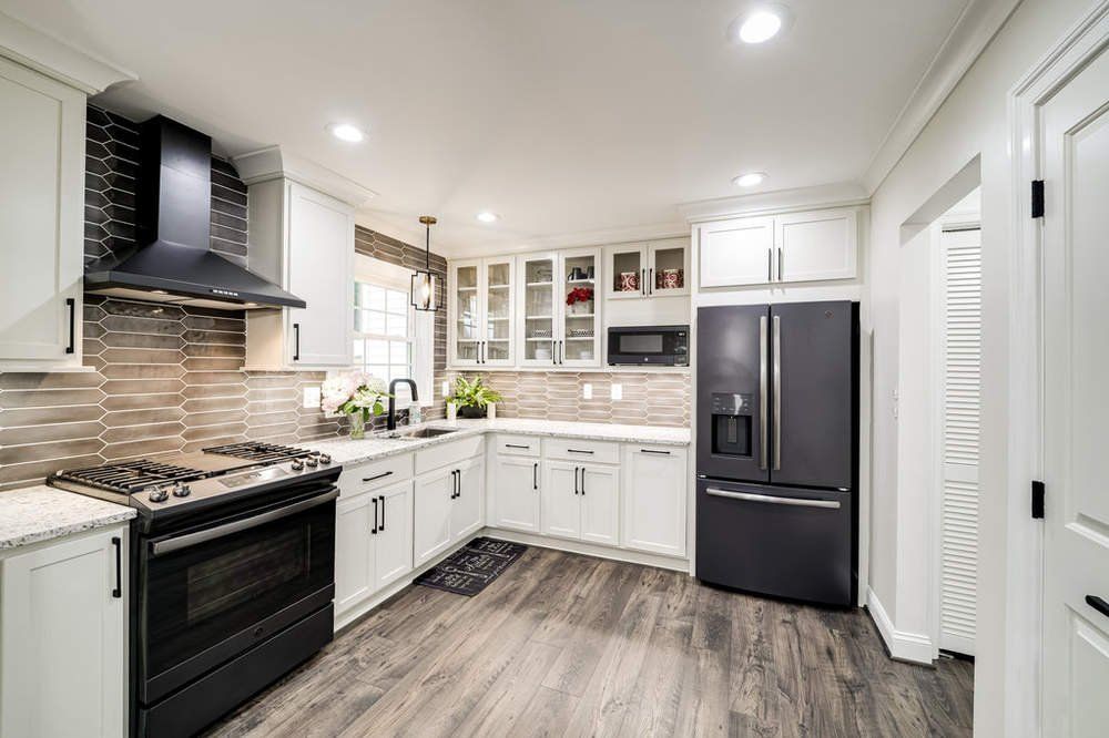 A kitchen with white cabinets , black appliances and a black refrigerator.