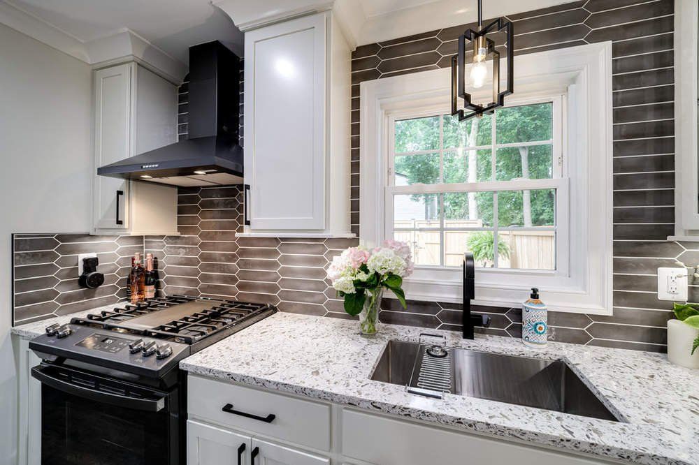 A kitchen with a stove , sink , and window.