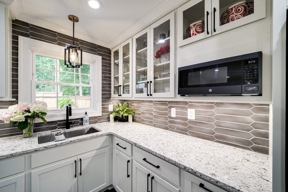 A kitchen with white cabinets , granite counter tops , a sink , and a microwave.