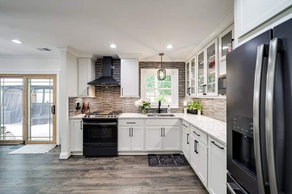 A kitchen with white cabinets , black appliances , and a black refrigerator.