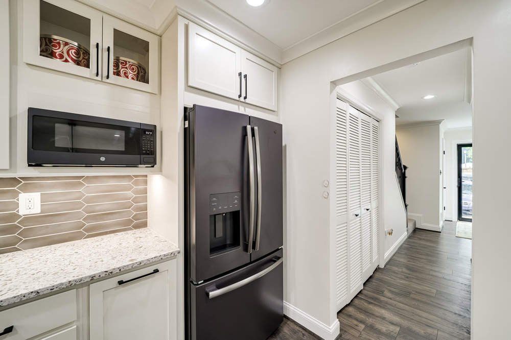 A kitchen with a black refrigerator and a microwave.