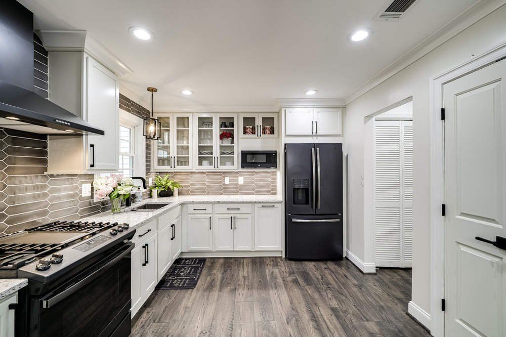 A kitchen with white cabinets , black appliances , and a black refrigerator.