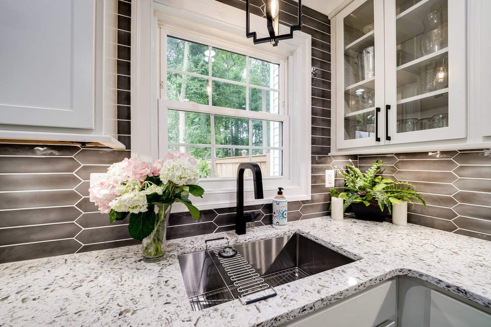 A kitchen sink with a vase of flowers next to it and a window.