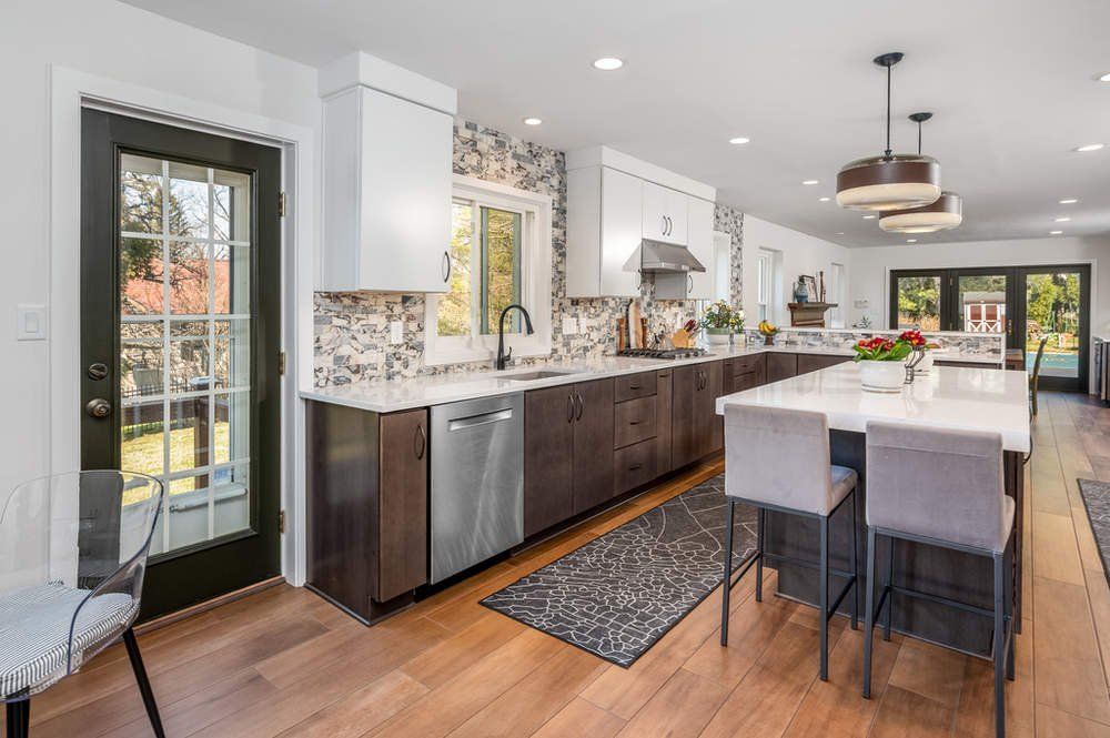 A kitchen with stainless steel appliances , wooden floors , and a large island.