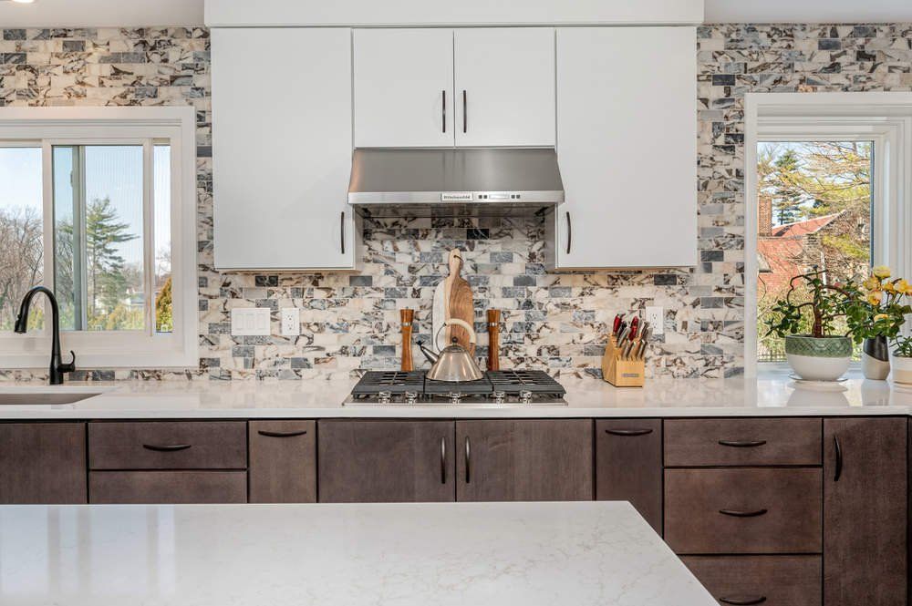 A kitchen with white cabinets , a stove , a sink , and a window.