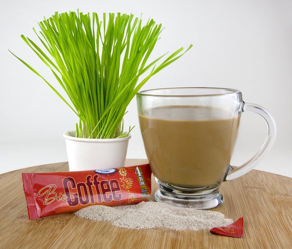 Cup of coffee with a cookie, wheatgrass in a pot, all on a wooden surface.