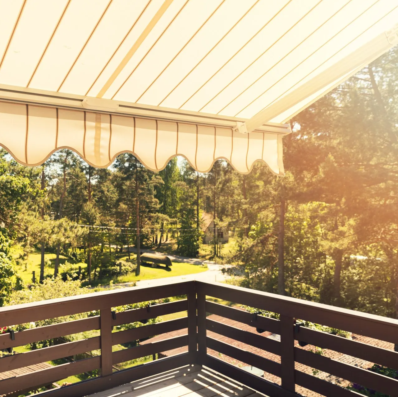 Sundrenched outdoor awning hanging over first floor timber balcony, overlooking treelined path.