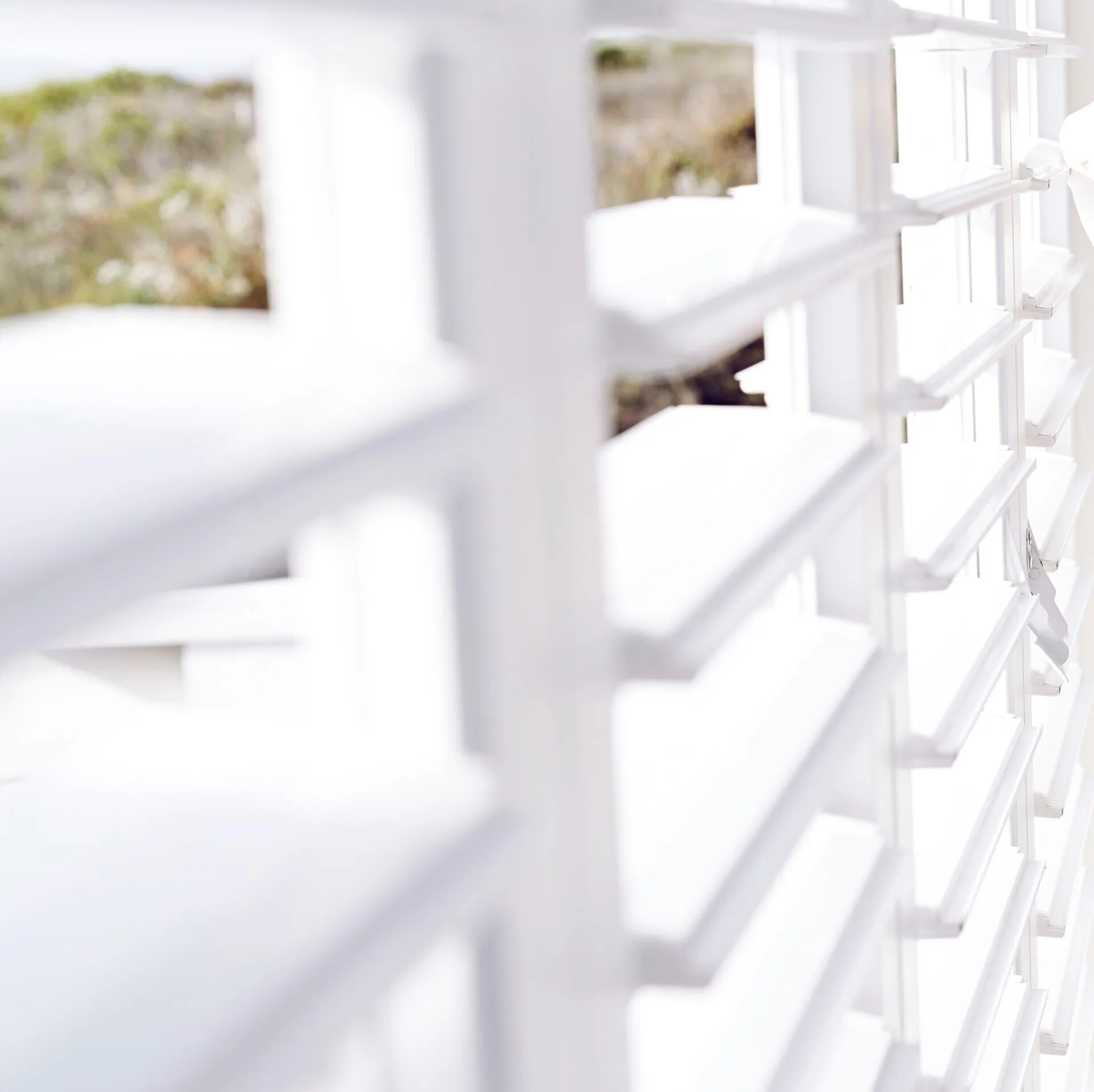 Close up view of white Plantation Shutters open to let in bright  sunlight.