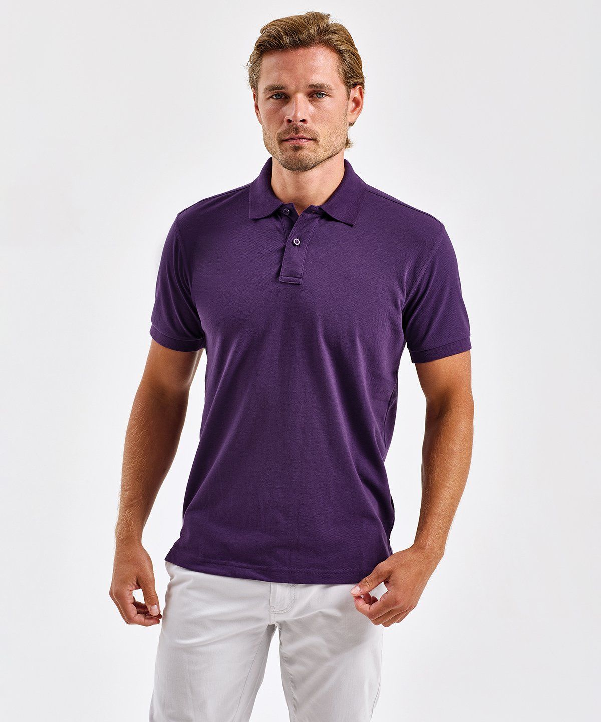 WhiteLodge Man wearing a purple polo shirt and white pants, standing against a white backdrop.