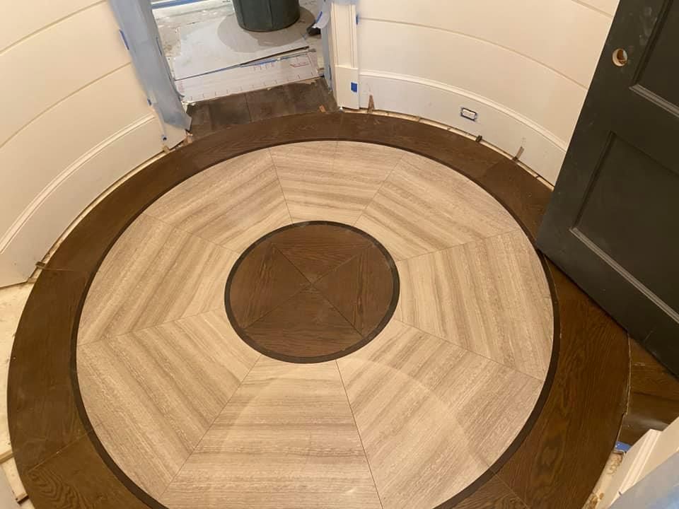 A circular wooden floor pattern featuring a dark center medallion, light wood radial planks, and a dark outer border.