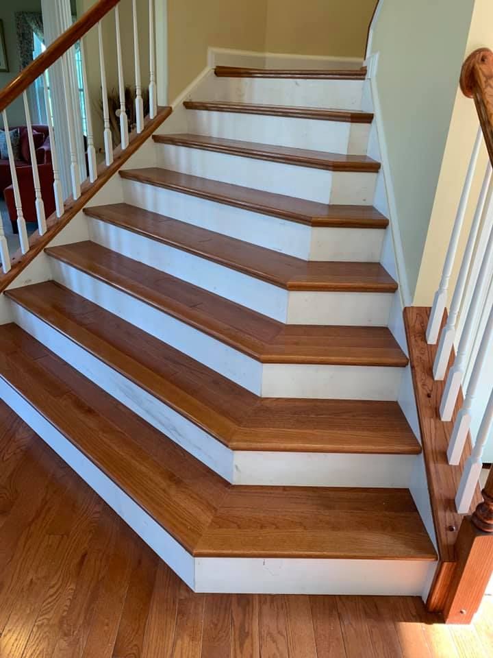 A staircase with wooden treads and white risers, featuring wooden banisters on both sides and a landing at the turn.