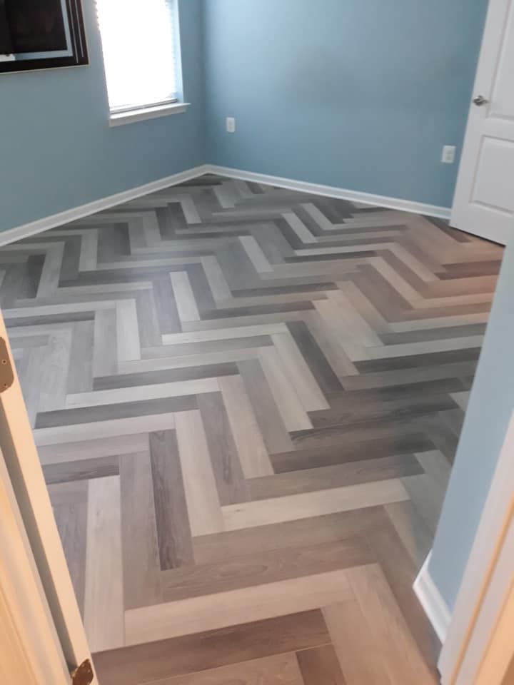 A room with blue walls and a multi-toned grey and beige wood floor laid in a herringbone pattern.