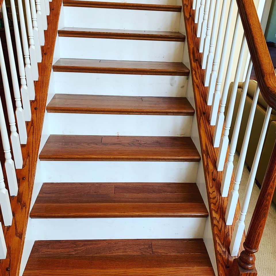 A wooden staircase with dark brown treads and white risers, featuring white balusters and a polished wood handrail.